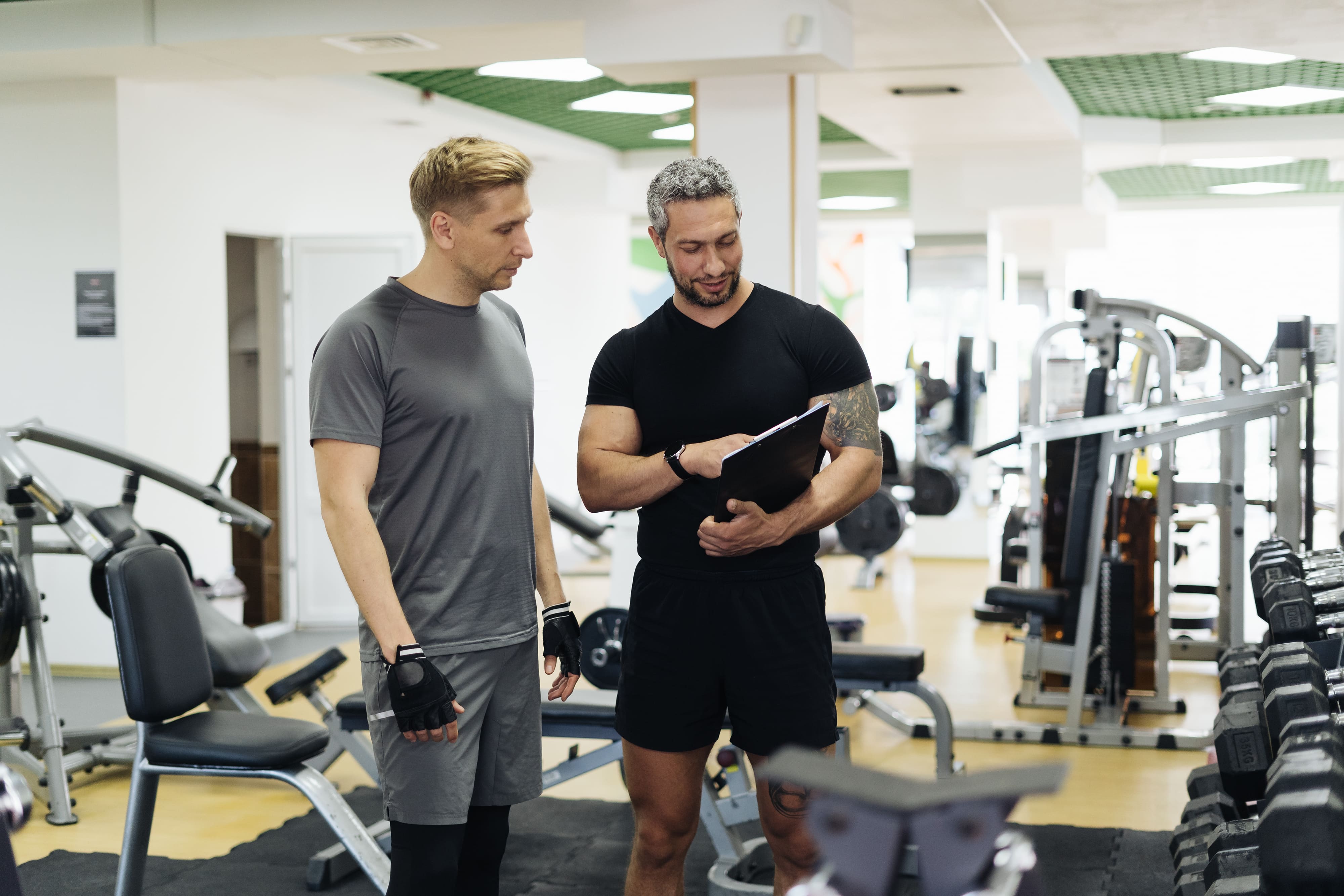 Un sporitf discute avec un coach sportif de plus de 30 ans en salle de sport